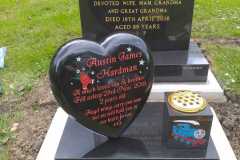 Heart-shaped black memorial plaque with red flowers