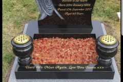 Black granite kerbed memorial with red and pink granite chips and brass urns