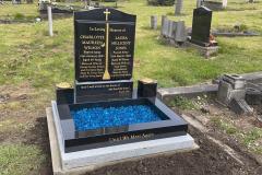 Black granite kerbed headstone with blue flower bed surround