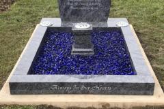 Dark blue stone grave with concrete edging and central plaque — Sleeping in God's Nursery