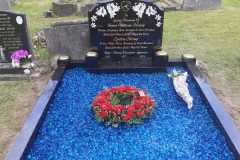 Black ornamental kerbed headstone with blue decorative stones