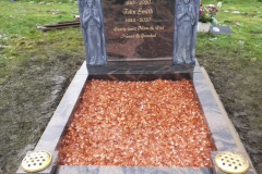 Slate religious headstone on white base with engraved inscription